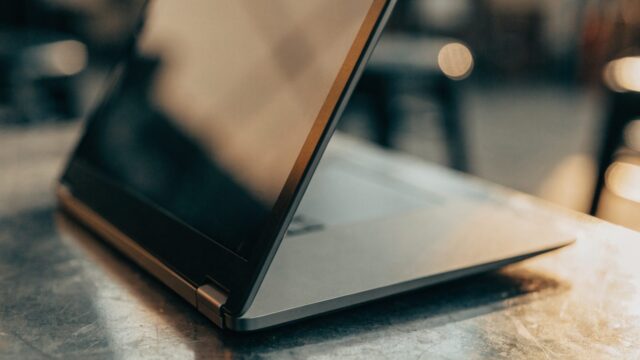 Close-up of the hinge and screen edge of a graphite black laptop on a workbench
