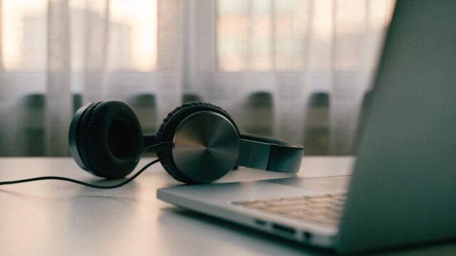 Over-ear headphones resting beside a silver laptop on a white desk