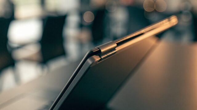 Close-up of the hinge and screen edge of a graphite black laptop on an office desk