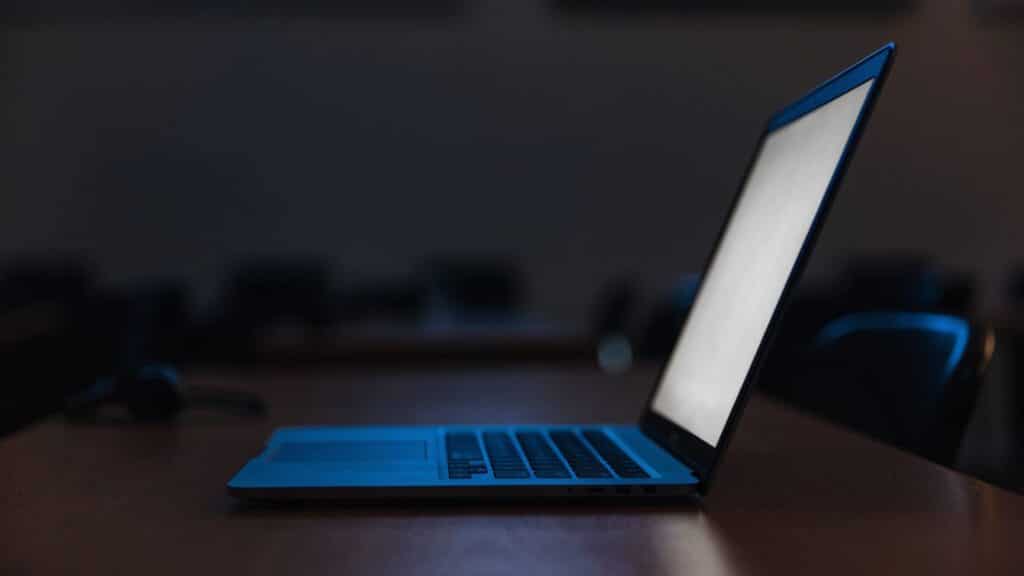 A dark blue laptop in a dark room
