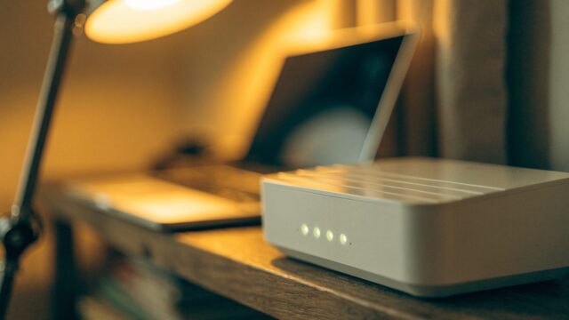A home wifi router with softly glowing indicator lights on a shelf