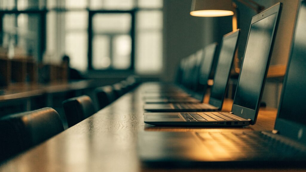 A row of laptops on desks in a school computer lab