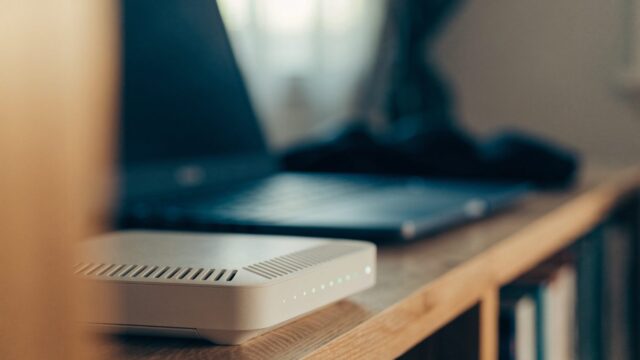 A home wifi router with softly glowing indicator lights on a shelf