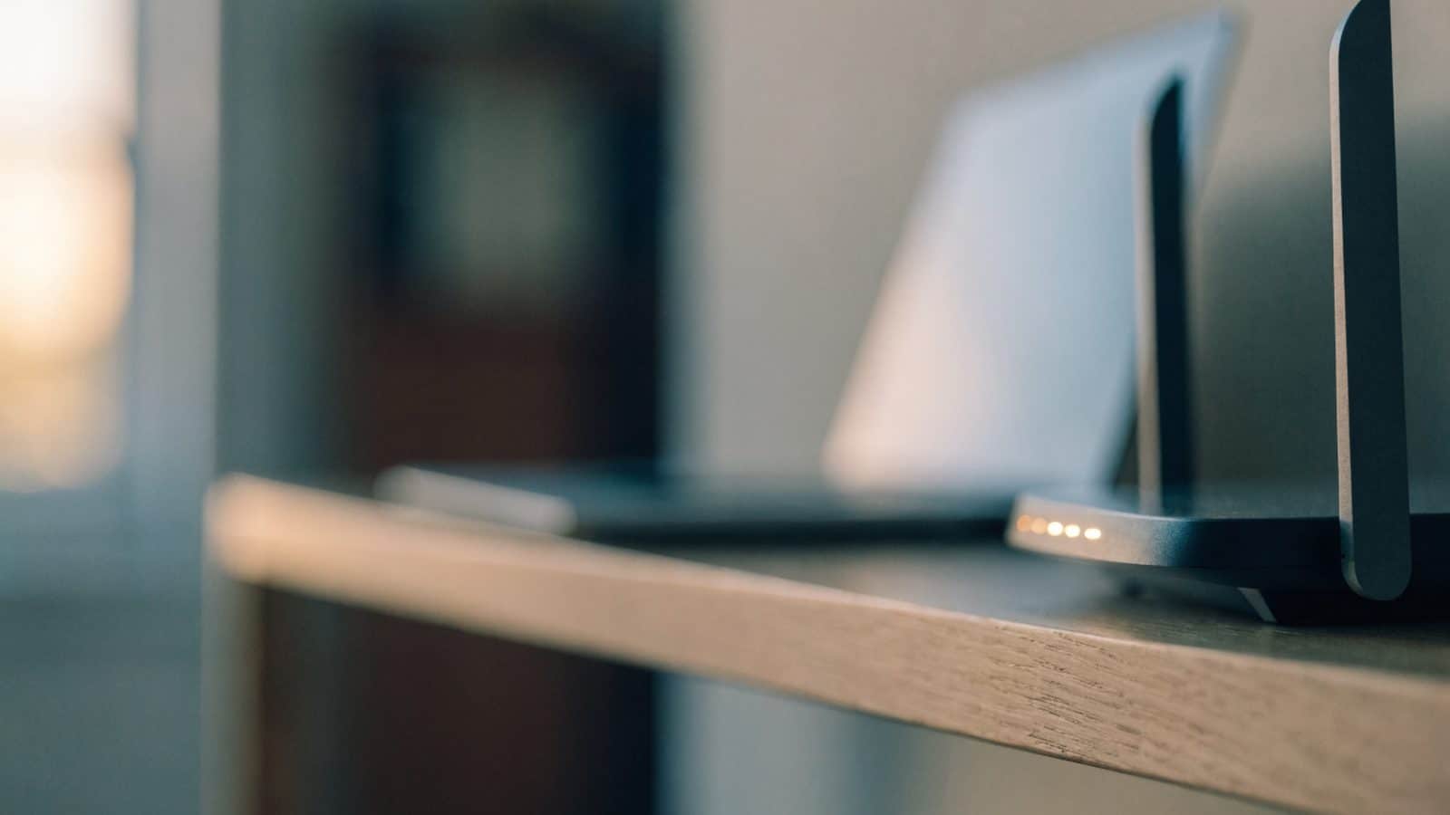 A home wifi router with softly glowing indicator lights on a shelf