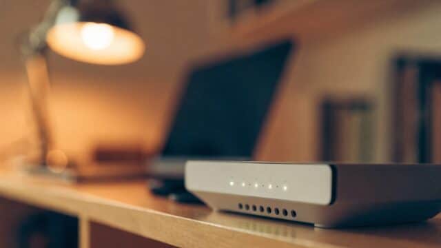 A home wifi router with softly glowing indicator lights on a shelf