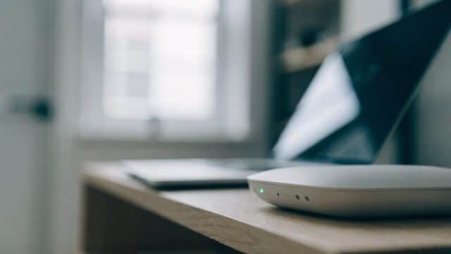 A home wifi router with softly glowing indicator lights on a shelf