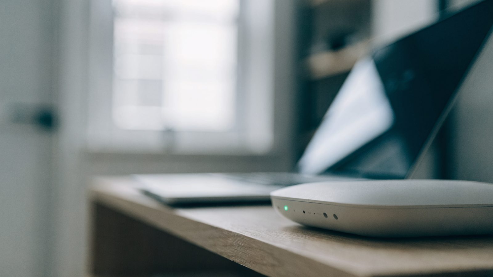 A home wifi router with softly glowing indicator lights on a shelf