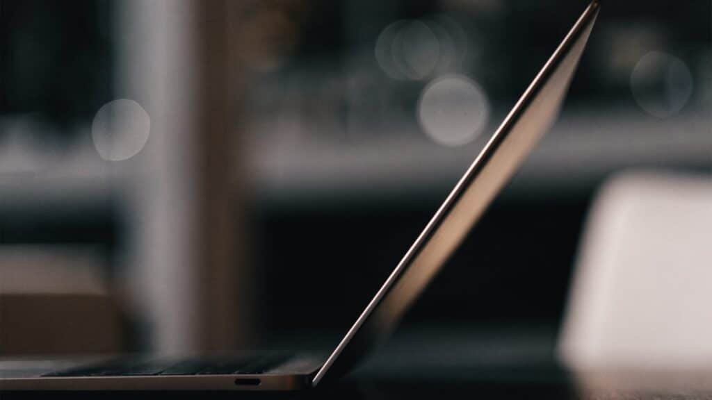 A slim matte grey laptop half open photographed from the side