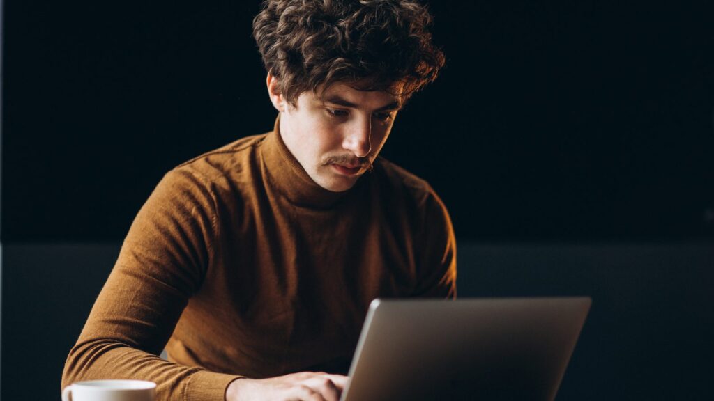 Man checking for a ChromeOS update on his laptop while drinking coffee
