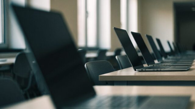 A row of laptops on desks in a school computer lab