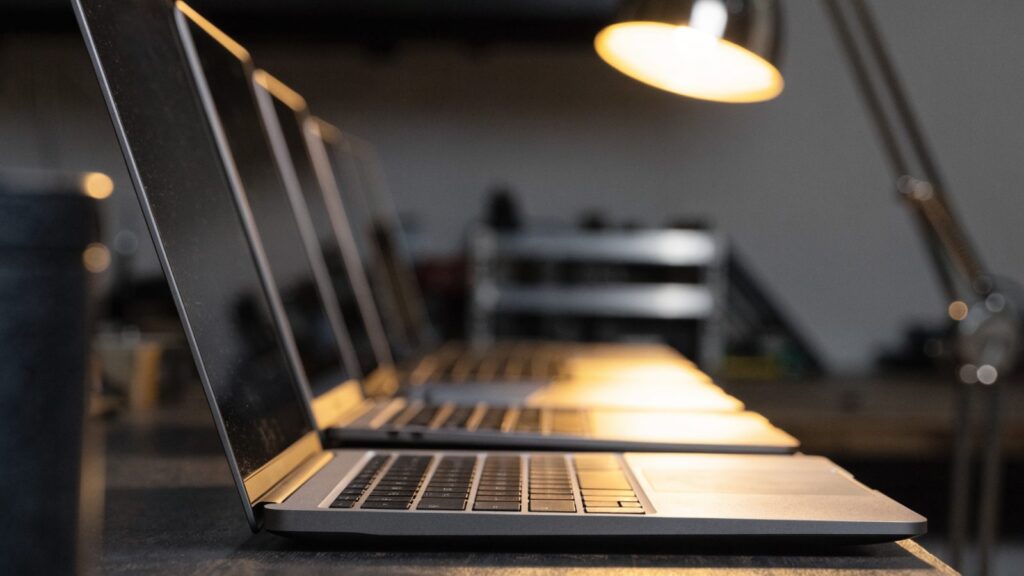 Several modern laptops lined up in a row on a workbench