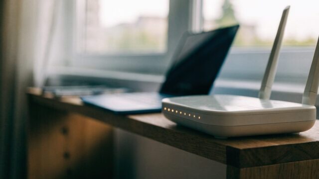 A home wifi router with softly glowing indicator lights on a shelf