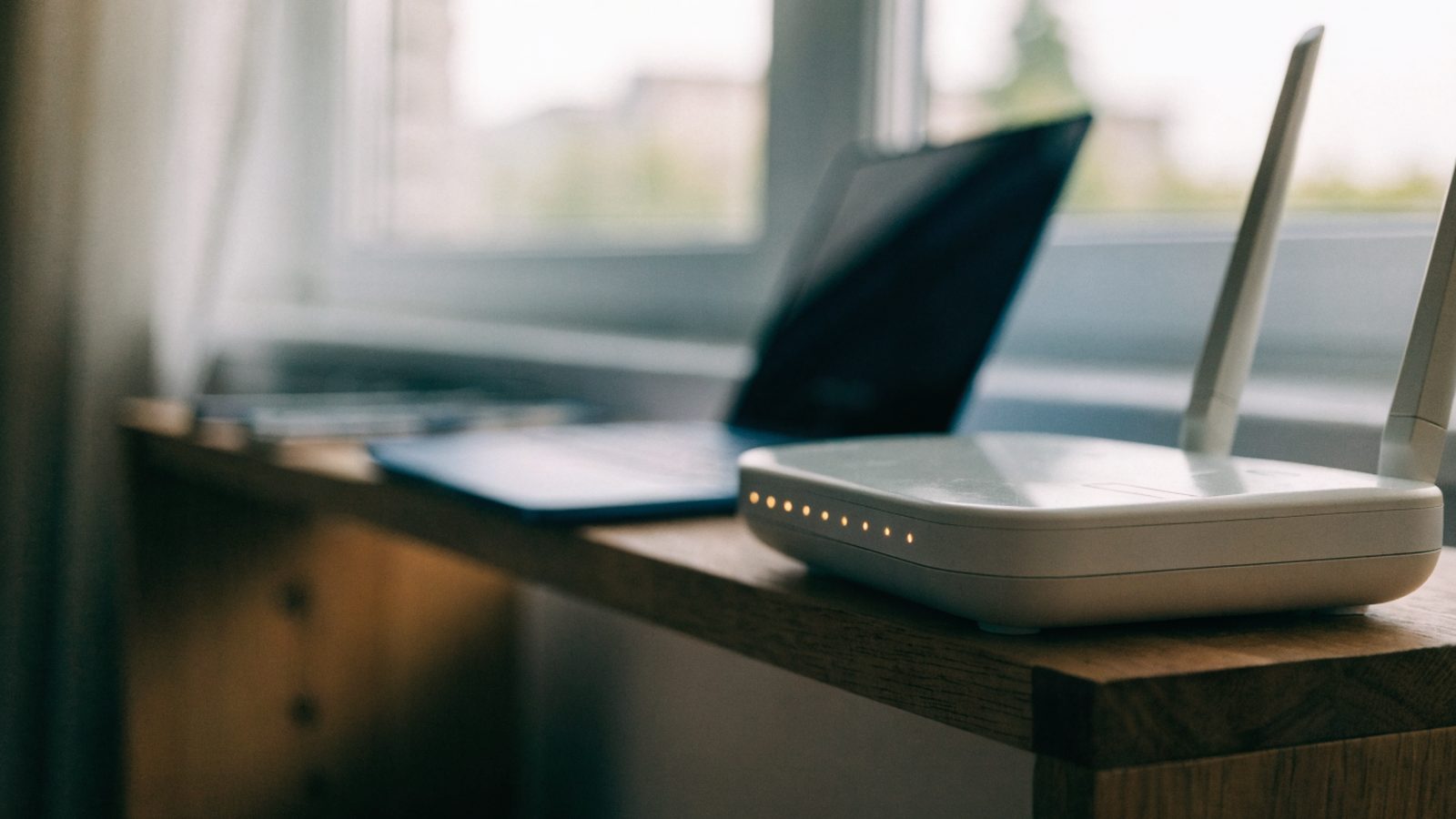 A home wifi router with softly glowing indicator lights on a shelf