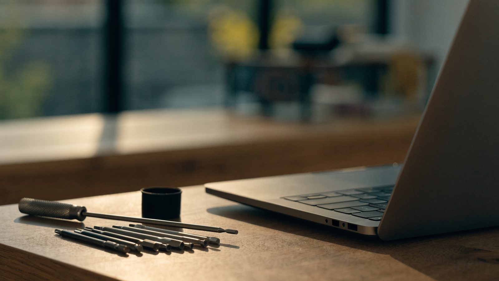 Hands typing on the keyboard of a matte grey laptop on a white desk