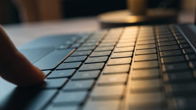 Close-up of a single key being pressed on a graphite black laptop keyboard