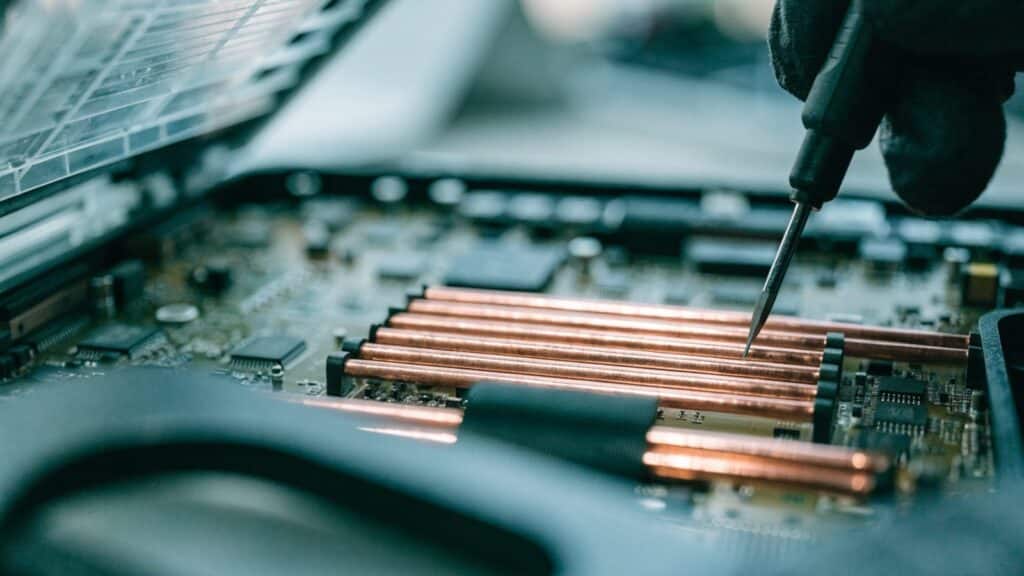 Close-up of a laptop motherboard with copper heat pipes during a repair