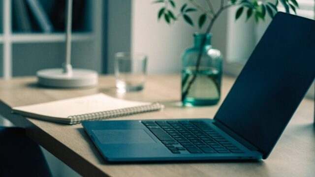 A tidy home office desk with a dark blue laptop