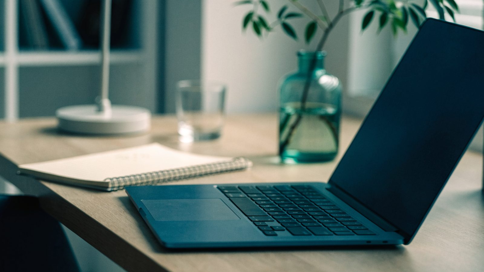 A tidy home office desk with a dark blue laptop