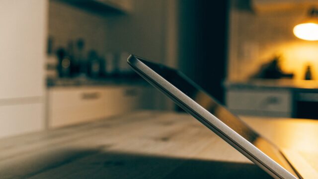 Close-up of the hinge and screen edge of a silver laptop on a kitchen table