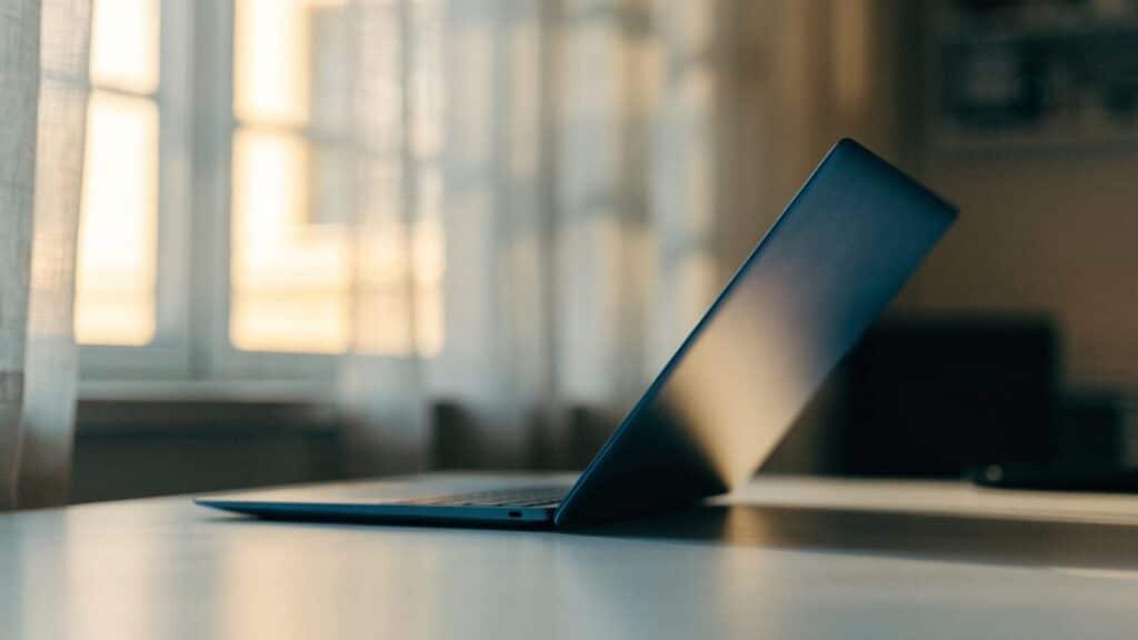 A half-closed dark blue laptop on a white desk