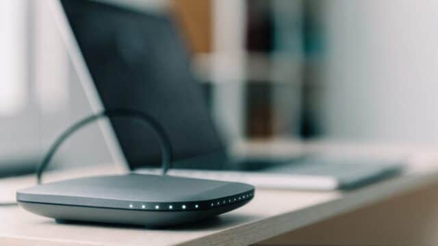 A home wifi router with softly glowing indicator lights on a shelf