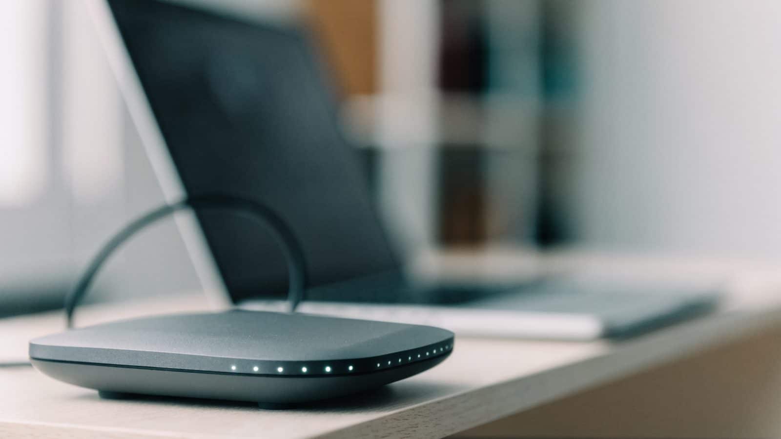 A home wifi router with softly glowing indicator lights on a shelf