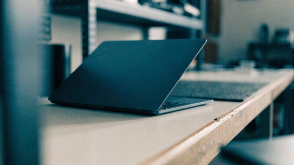 A half-closed dark blue laptop on a workbench