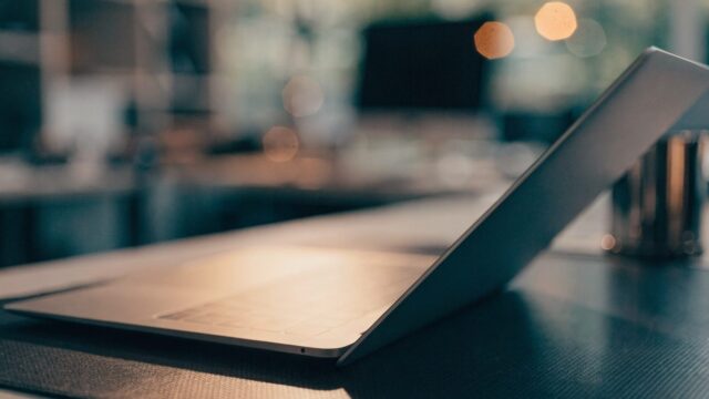 A half-closed matte grey laptop on a dark desk mat