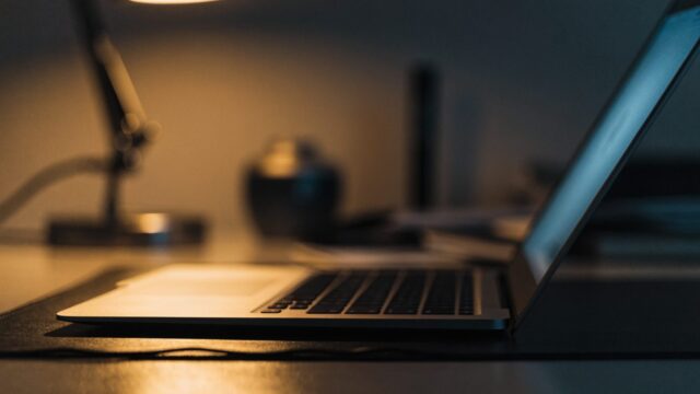 A half-closed matte grey laptop on a dark desk mat