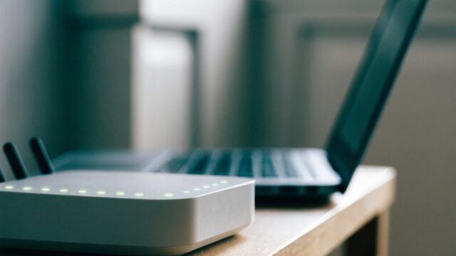 A home wifi router with softly glowing indicator lights on a shelf