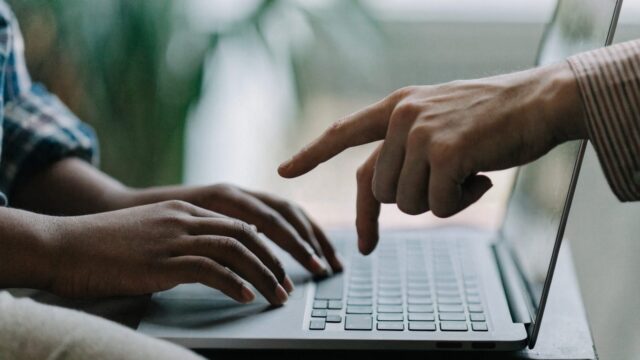 A child's hands on a matte grey laptop keyboard
