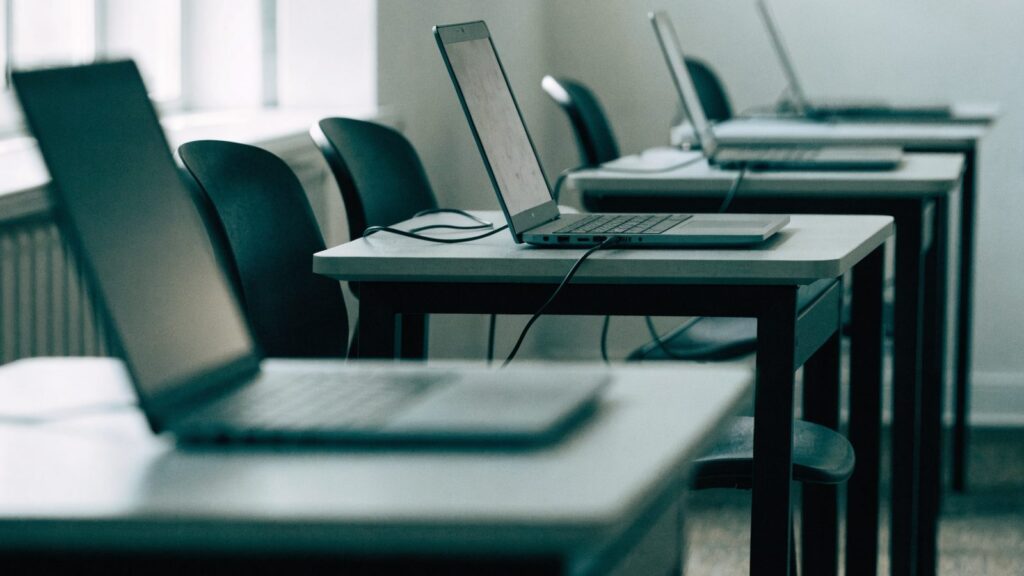 A row of laptops on desks in a school computer lab