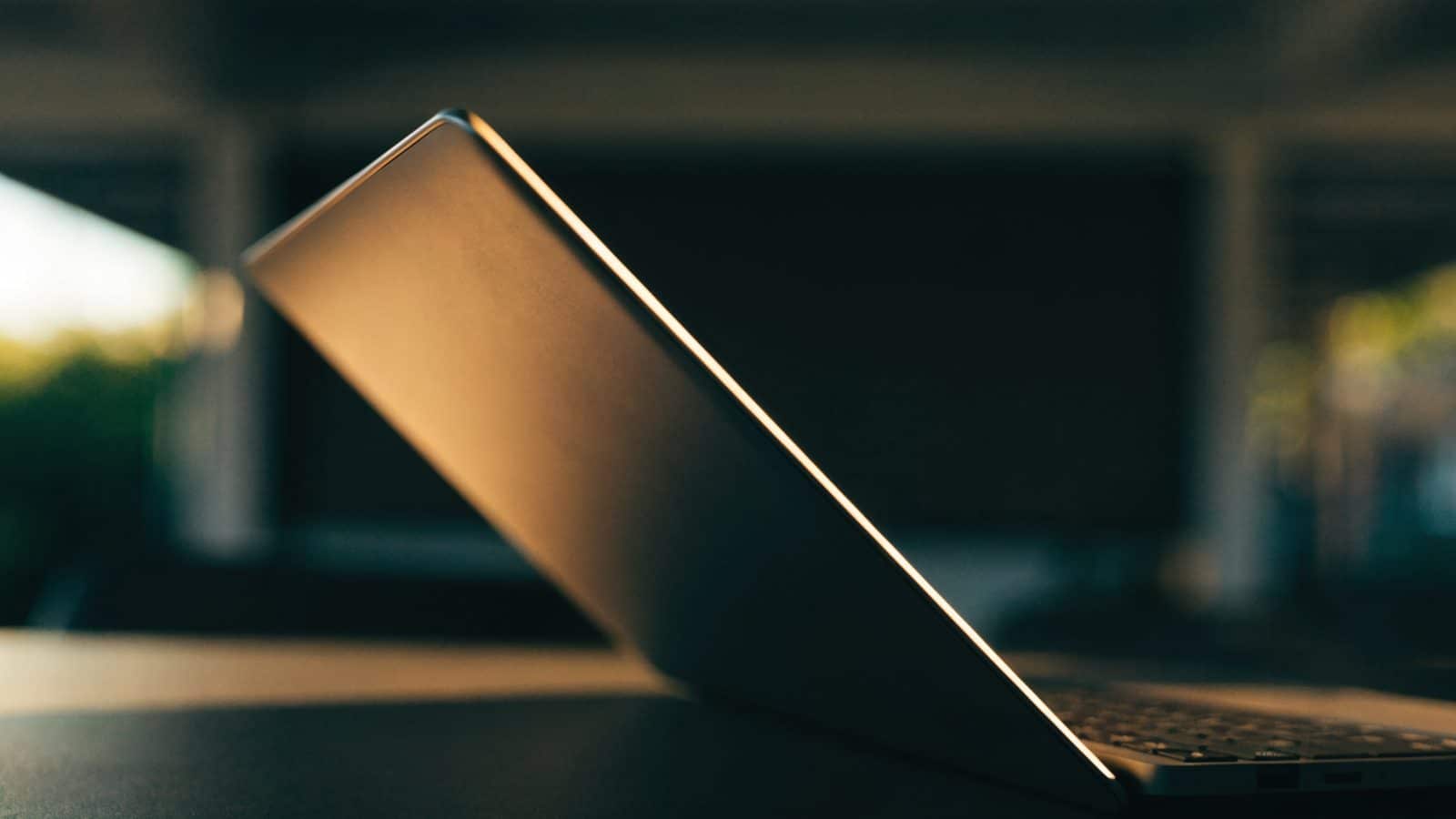 A slim graphite black laptop half open photographed from the side