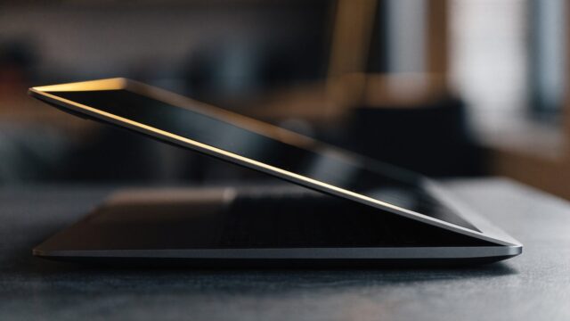 A slim graphite black laptop half open photographed from the side