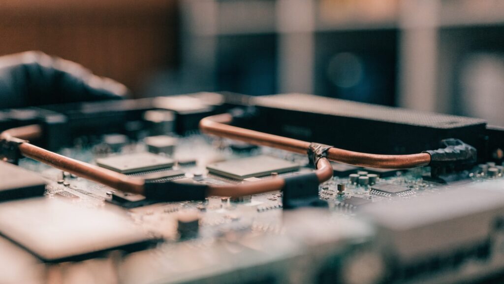 Close-up of a laptop motherboard with copper heat pipes during a repair