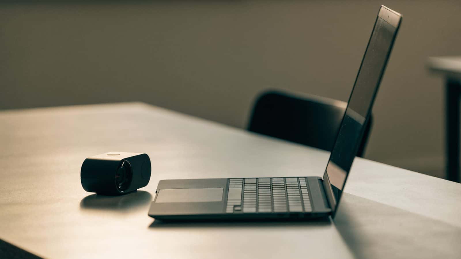 A graphite black laptop beside a small projector on a table