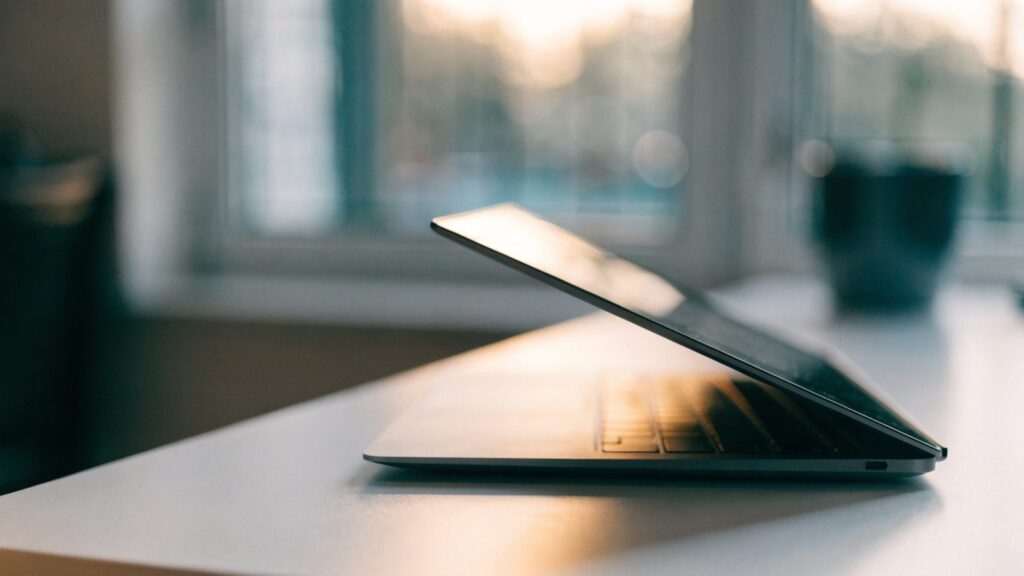 A half-closed graphite black laptop on a white desk