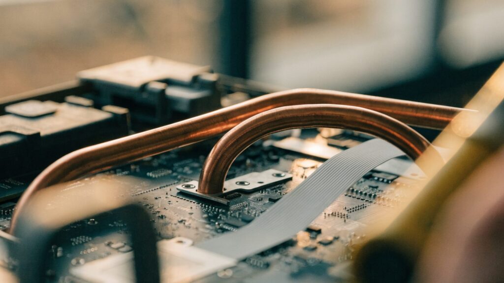 Close-up of a laptop motherboard with copper heat pipes during a repair