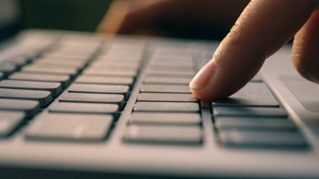 Close-up of a single key being pressed on a matte grey laptop keyboard