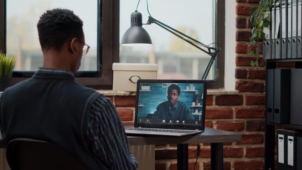 Startup employee using remote video call on laptop to talk to colleague at job. Man attending business…