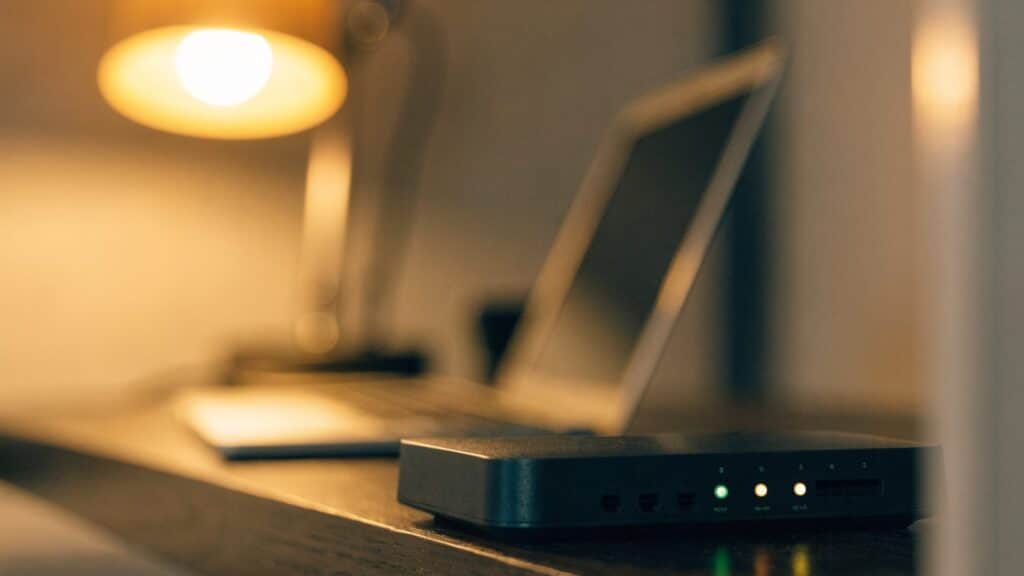 A home wifi router with softly glowing indicator lights on a shelf