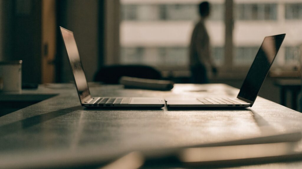 Two laptops side by side on a workbench as if being compared