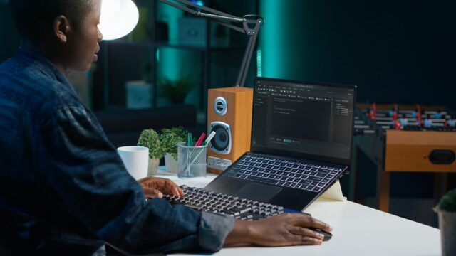 Freelancing admin in home office using laptop to write programming language code