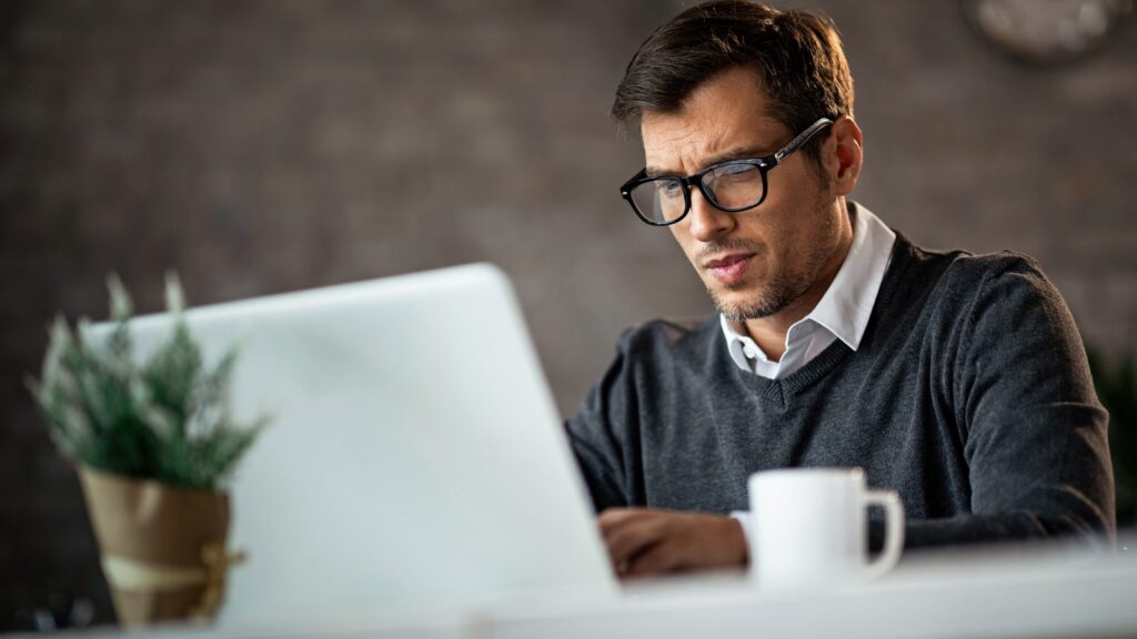 Low angle view of freelance worker using laptop and typing and email while being at work