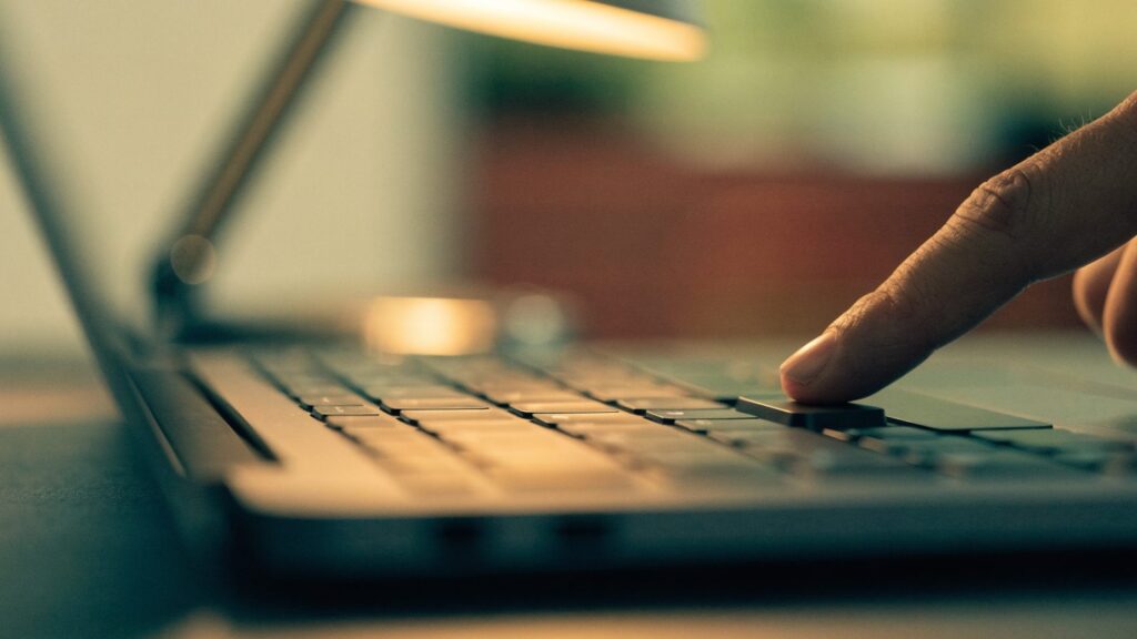 Close-up of a single key being pressed on a graphite black laptop keyboard