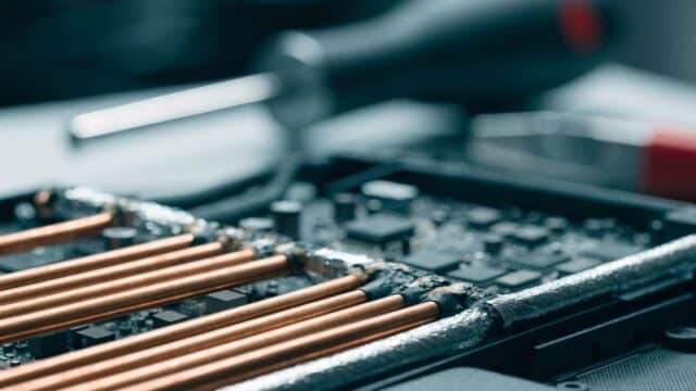Close-up of a laptop motherboard with copper heat pipes during a repair