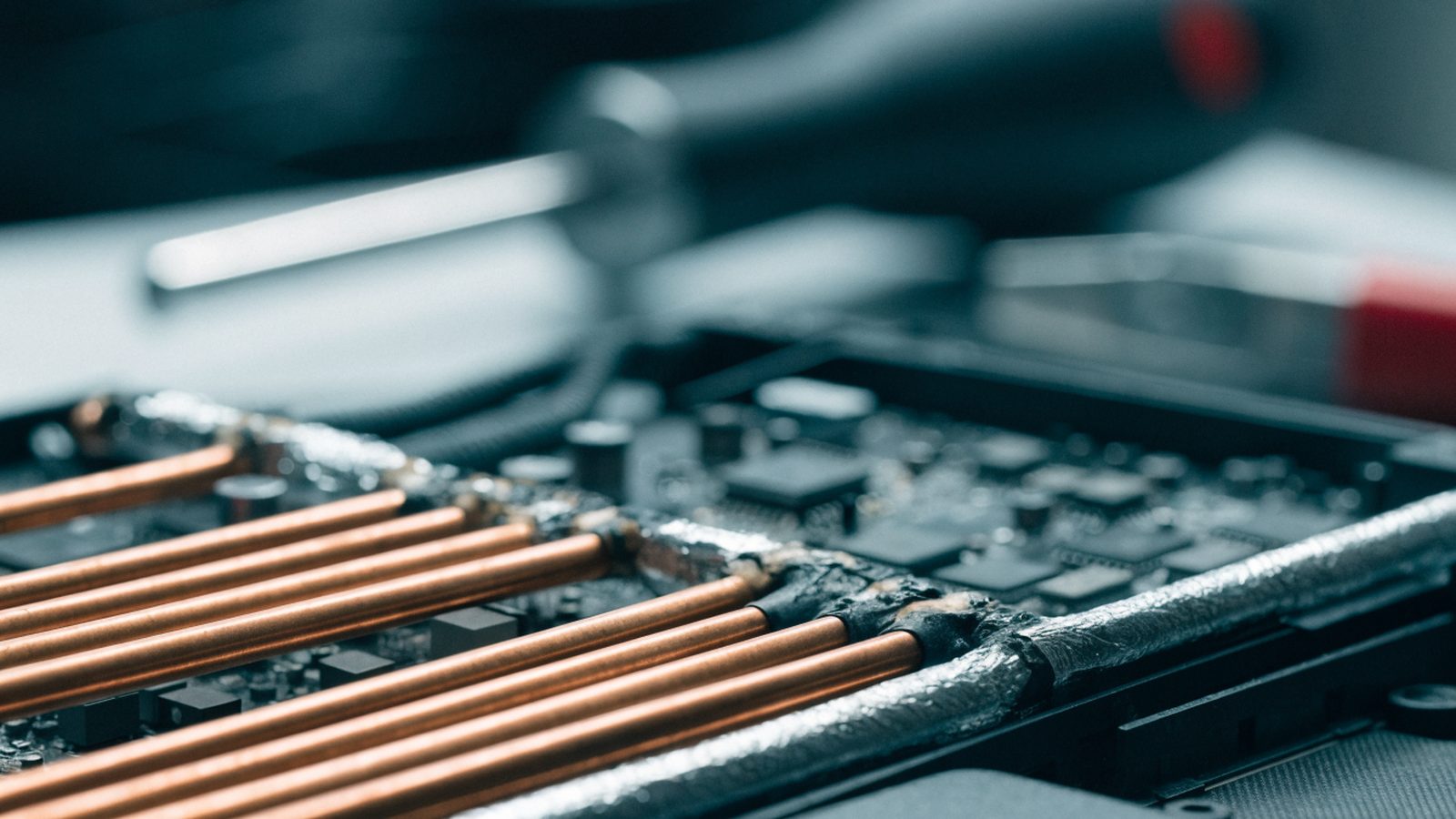 Close-up of a laptop motherboard with copper heat pipes during a repair
