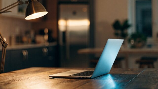 A half-closed silver laptop on a kitchen table