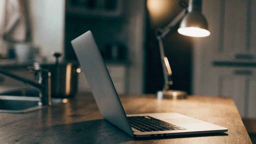 A half-closed silver laptop on a kitchen table
