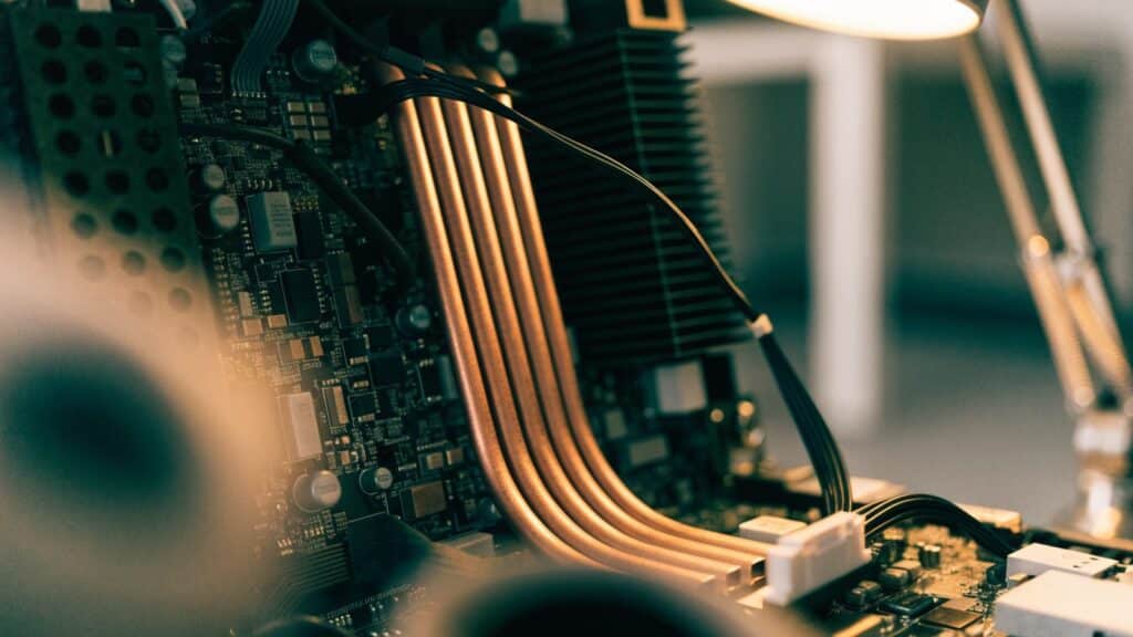 Close-up of a laptop motherboard with copper heat pipes during a repair